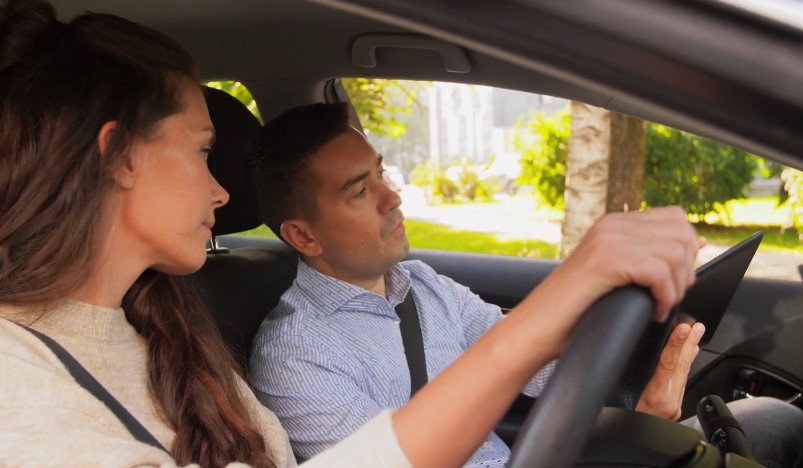 A driving instructor guides a student through a lesson