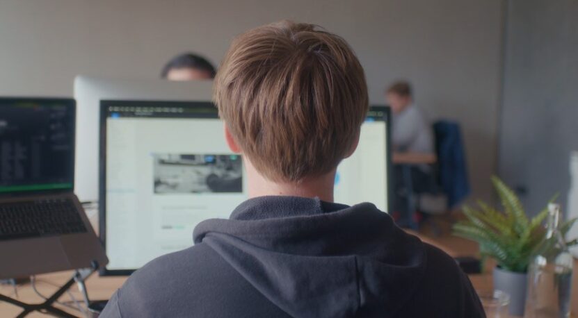 Focused developer engrossed in a project, multiple screens displaying various tasks