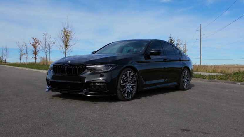 Black BMW G30 sedan parked on open road