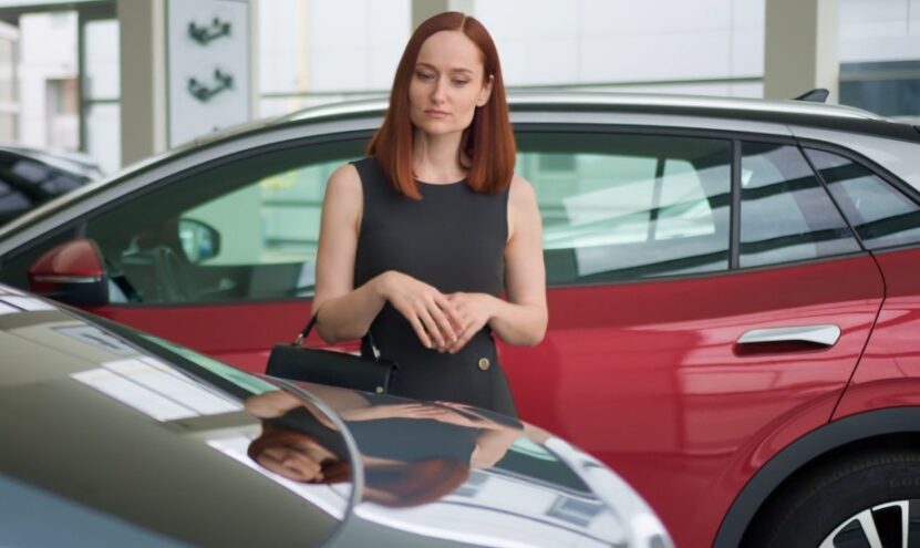 A woman examines a car on display in a modern showroom