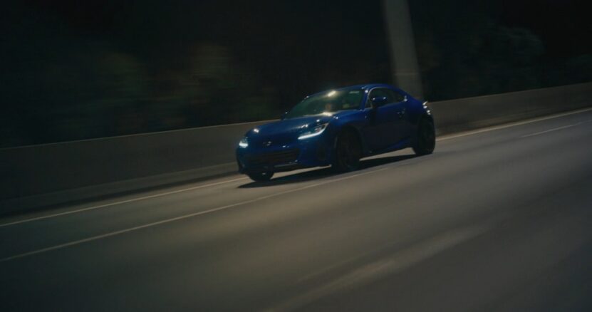 Blue sports car speeding on the highway at night