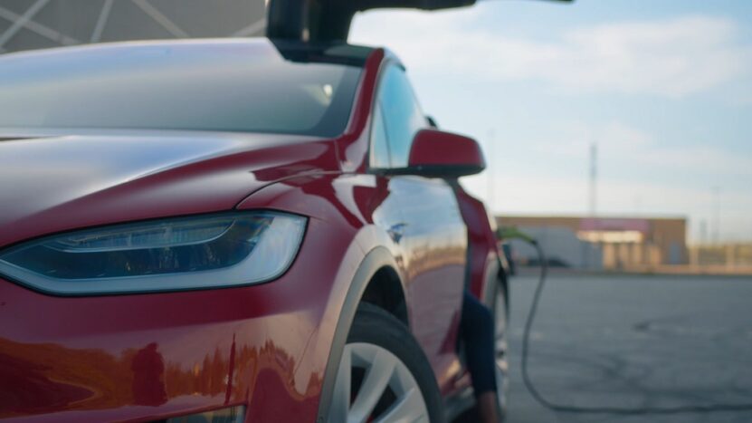 Red electric car charging at a station, highlighting how car weight affects EV efficiency