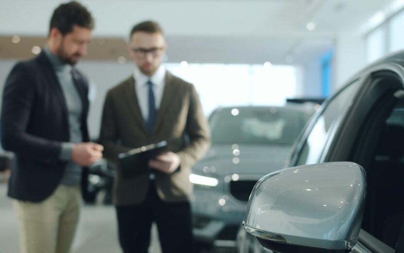 Two men in suits examining a car in a modern showroom setting