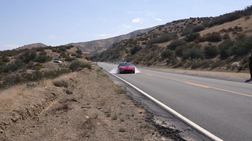Red sports car performing an emergency brake on a mountain road