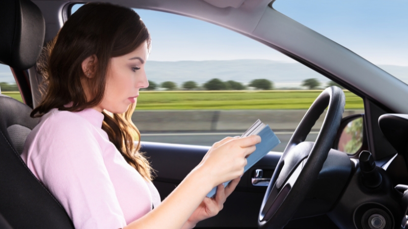 A woman reads a comic book while driving, which is banned in Oklahoma