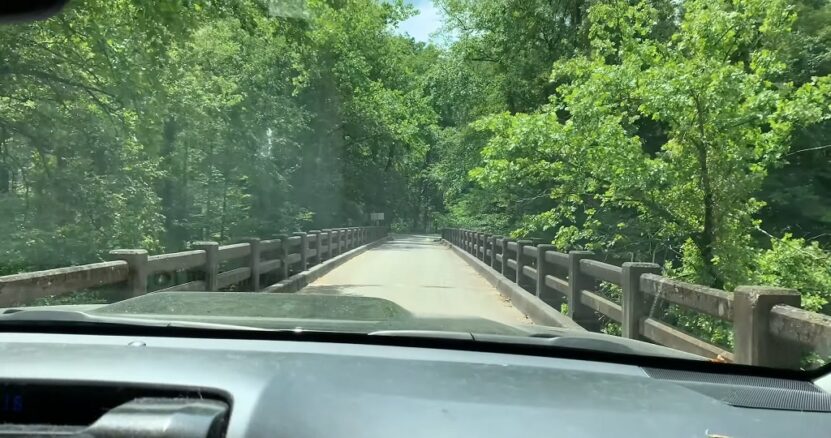 Driving across a narrow bridge surrounded by lush forest on Red River Gorge Scenic Byway