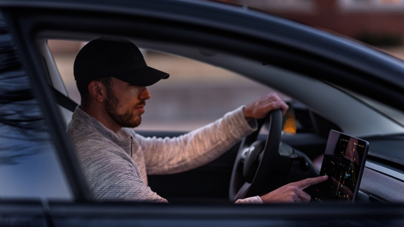 A Texas driver uses a car’s touchscreen, reflecting 2025 laws that demand greater responsibility behind the wheel