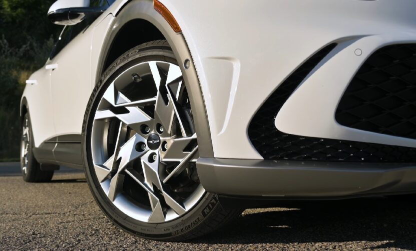 Close-up of a white car’s wheel, showing tire wear patterns