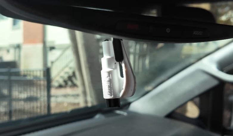 Car safety escape tool suspended on a car's mirror