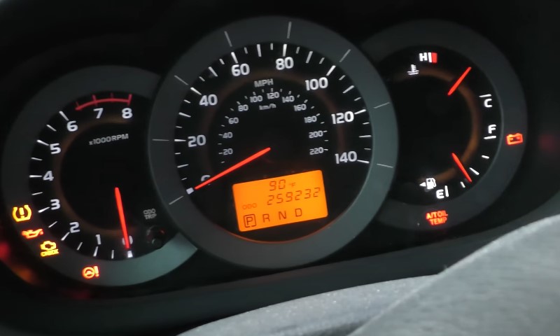 Dashboard lights illuminate: Engine RPM near zero, speed low, several warning indicators glowing orange and red against the dark gauge cluster