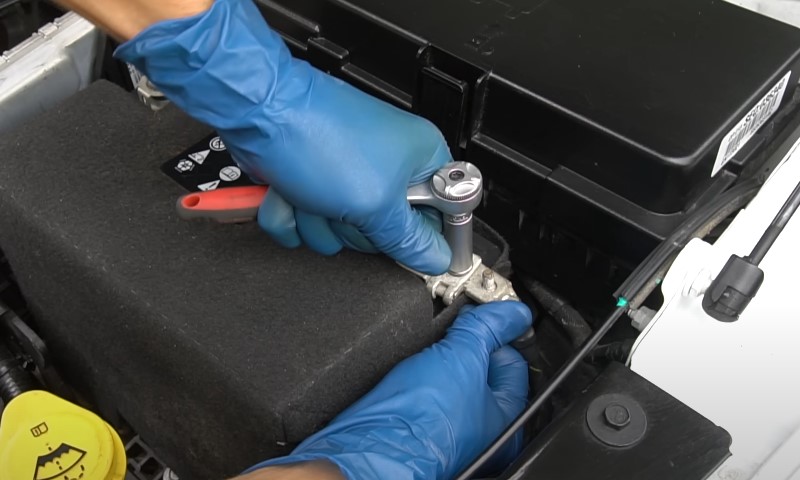 Mechanic repairing fuel system, wearing blue gloves