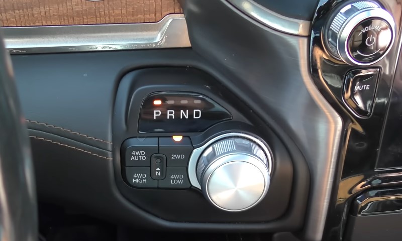 Close-up of a vehicle's center console shows a rotary gear selector with labels P, R, N, D