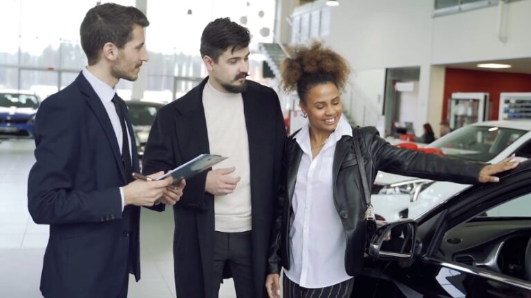 People looking at a vehicle inside a modern car dealership showroom