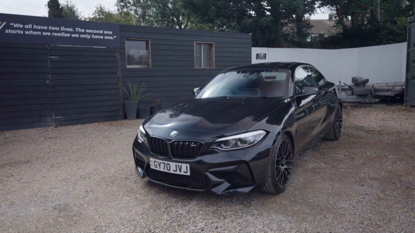 Black BMW M2 F87 shown from a front three-quarter angle on a gravel surface