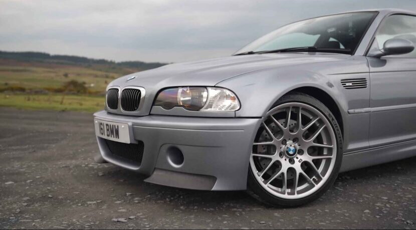 Silver BMW M3 CSL photographed from the front-left angle on a quiet countryside road