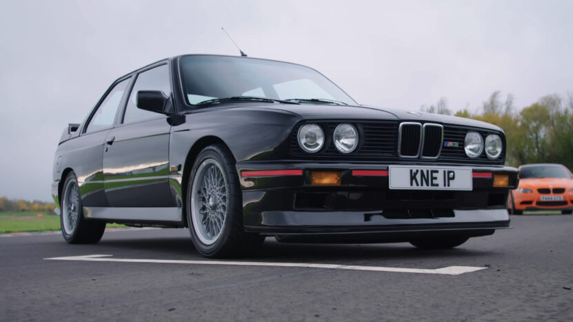 Black BMW M3 E30 shown from a low front-left angle on a paved track