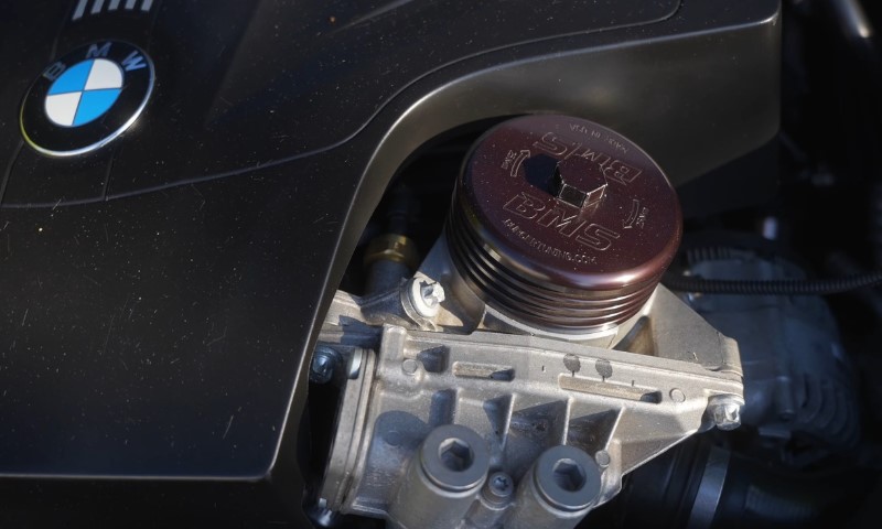 Close-up of a BMW engine part featuring a metallic component with "BMS" engraved on top