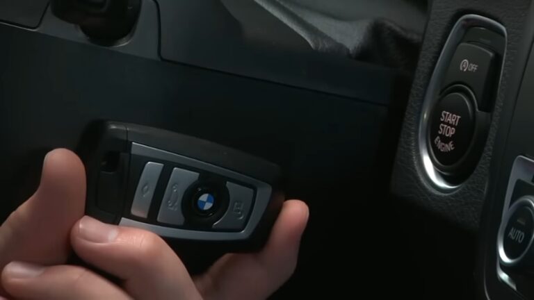 Hand holding a BMW Key Fob inside a car near the start-stop engine button