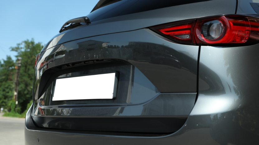 Rear view of a gray car with a visible license plate parked outdoors