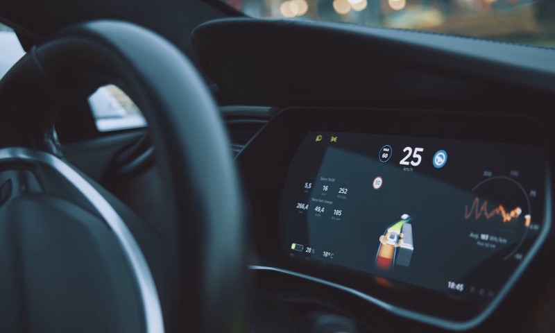 Close-up of a car dashboard screen displaying speed, energy consumption, and a navigation map