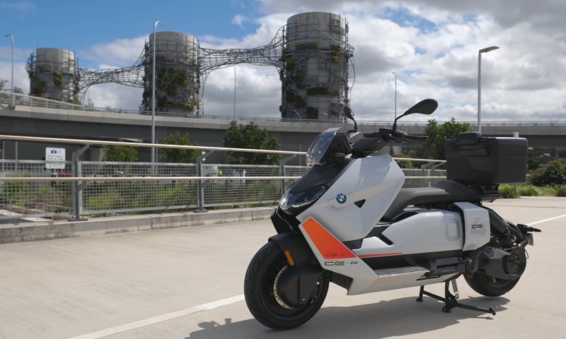 A sleek, modern electric scooter is parked under a partly cloudy sky