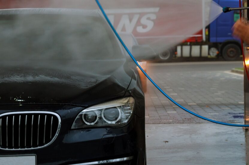 BMW car being washed with high pressure water before transport inspection